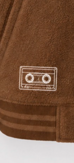 A small embroidered cassette tape motif on brown fabric